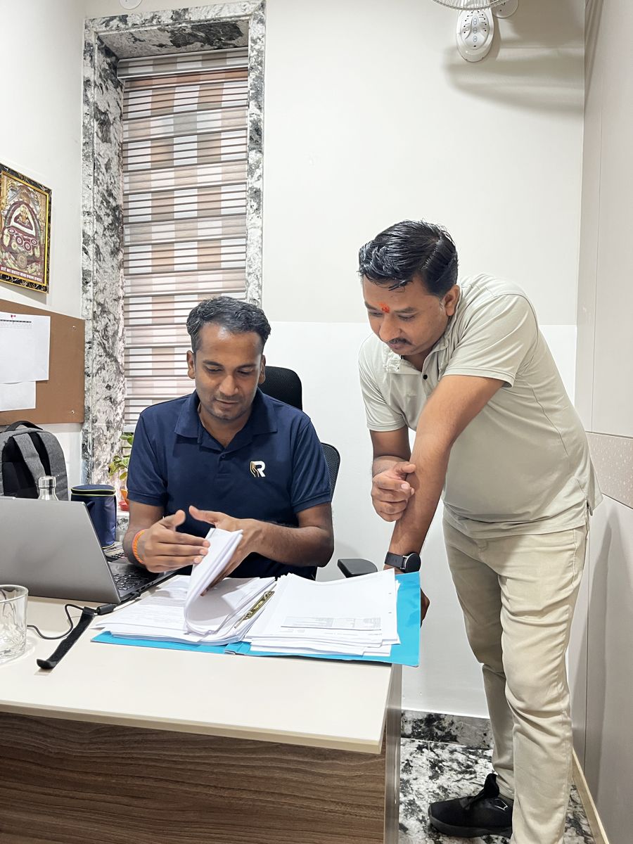 Two Ritwik Finance colleagues reviewing loan files at a desk